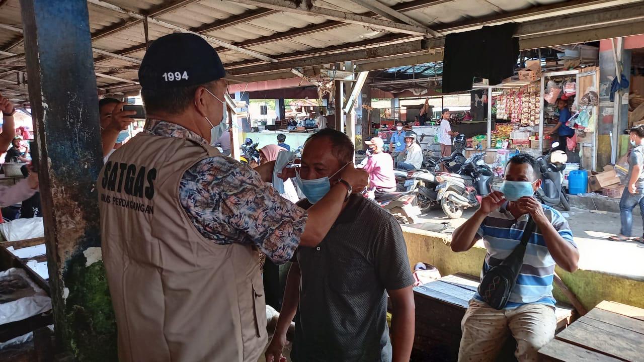 Dinas Perdagangan OKI saat memasangkan masker ke pedagang Pasar Kayuagung, Jumat (25/6)